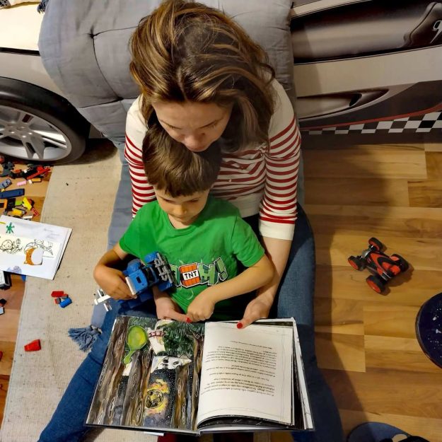 Майка е гушнала в скута си своето дете и му чете книгата Звездна одисея, в която се говори за емоциите