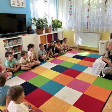 деца седнали в кръг говорят с авторката на книгата за котки и динозаври