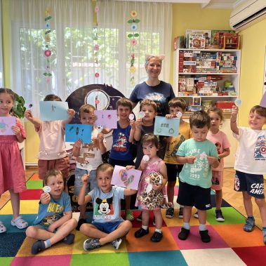 Обща снимка на много деца на фона на детска градина с авторката на звездна одисея Галя ненчева