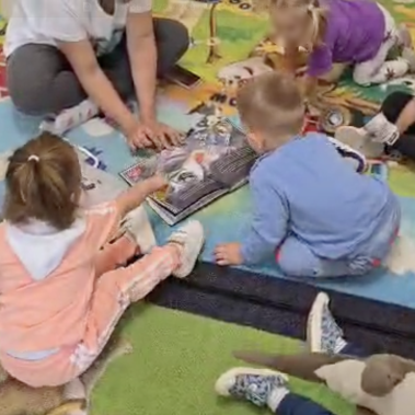 малки деца от ясла разгледжат книгата "звездна одисея"