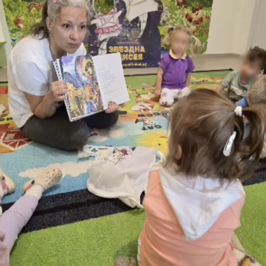 Галя Ненчева показва ярка илюстрация на Слънцето и обеснява на децата историята на Ая и Благо