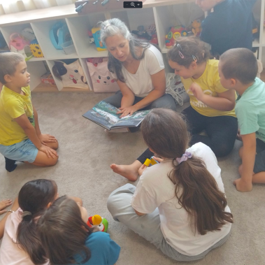 Галя Ненчева чете от своята книга Звездна одисея на деца насядали в кръг около нея